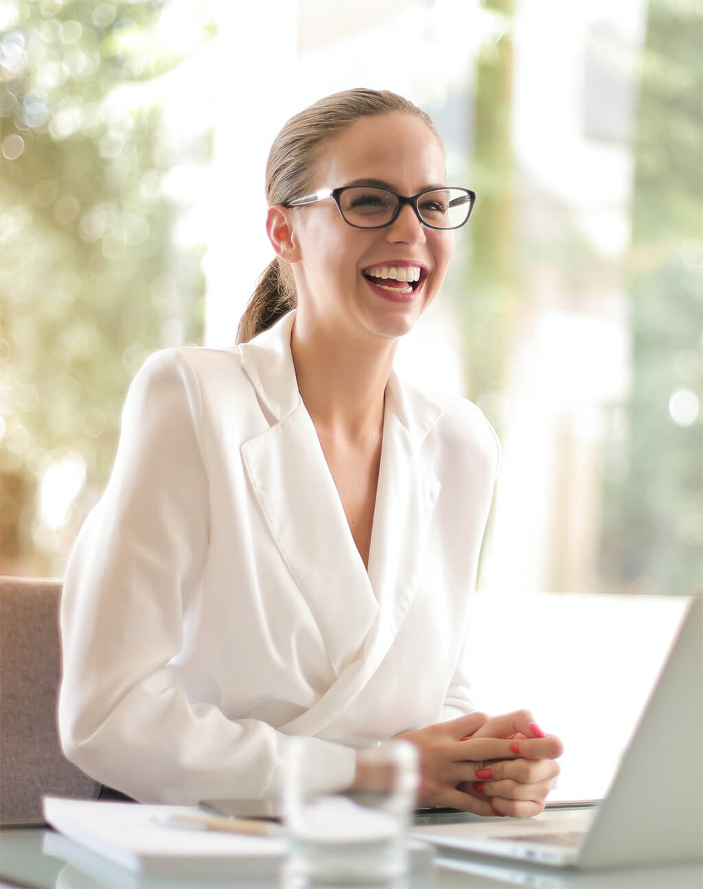 lady in white smiling in front of a laptop